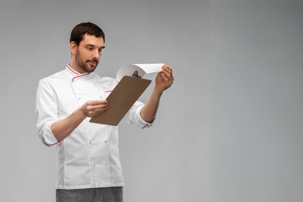 Chef reviewing paperwork on clipboard