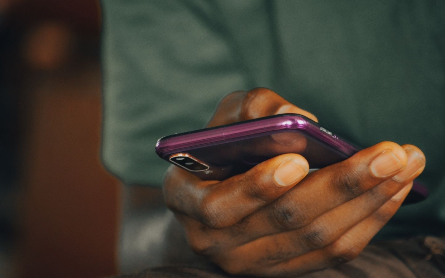 A hand holding a purple mobile phone