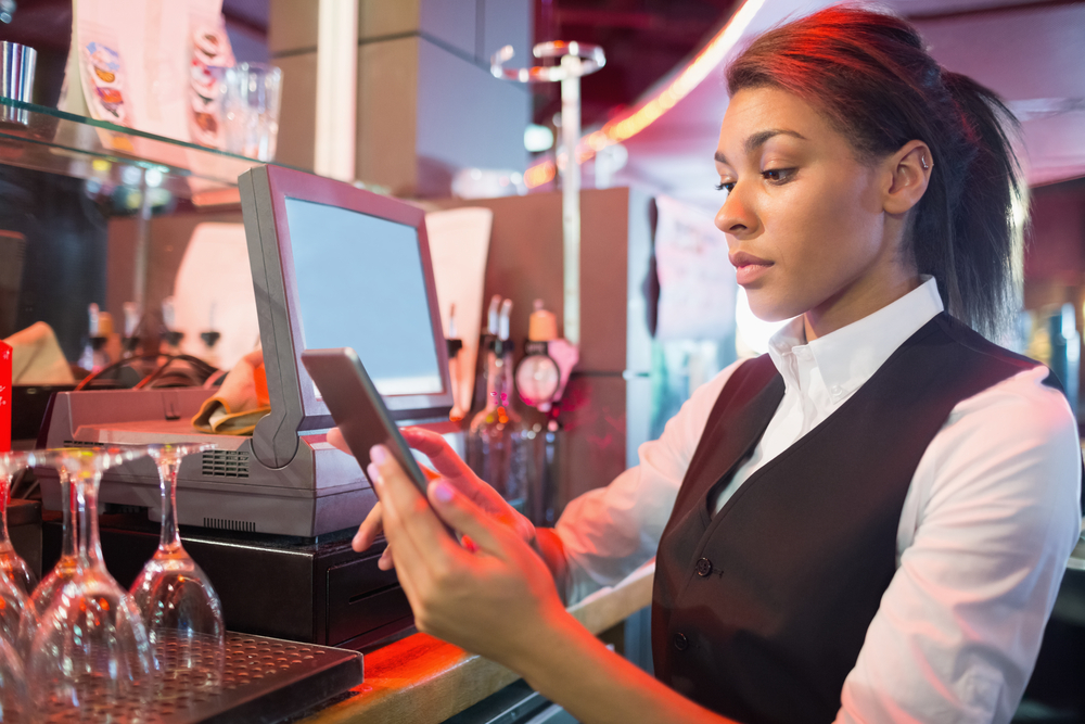 Pretty barmaid using touchscreen till in a bar Pretty barmaid using touchscreen till in a bar