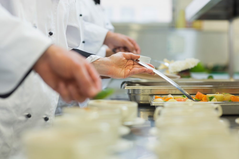 Chefs standing in a row preparing food in a modern kitchen.jpeg