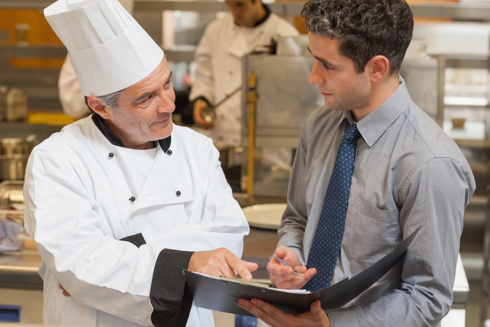 Waiter and chef discussing the menu in the kitchen