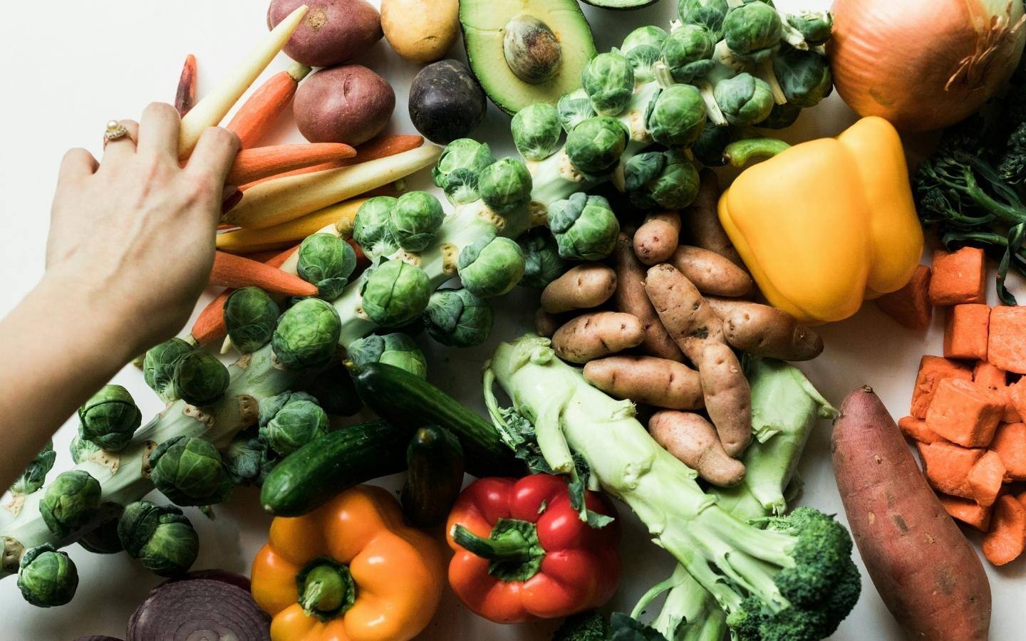 An assortment of vegetables including broccoli, carrots, pepper, kumara and sprouts on a table