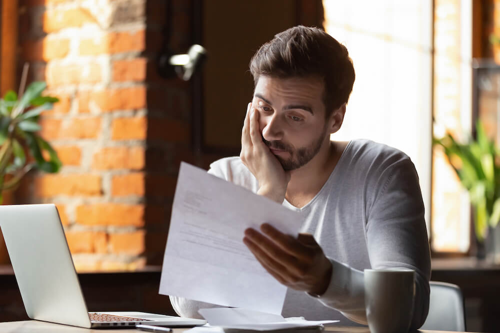 Man with paperwork in cafe with laptop small
