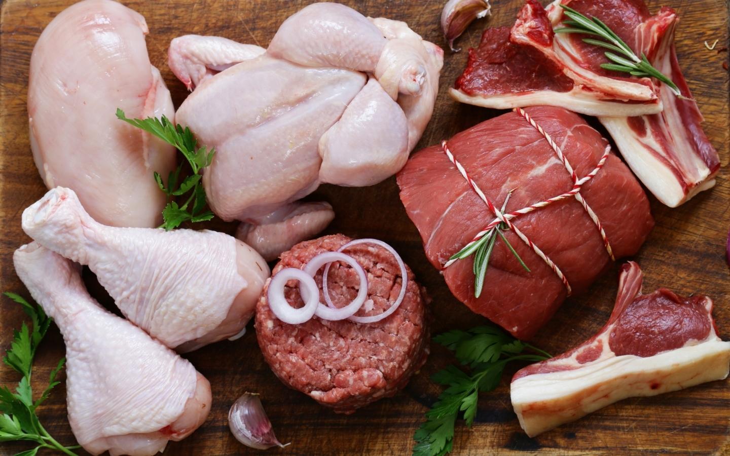 An assortment of raw red meats and poultry sat on a wooden surface