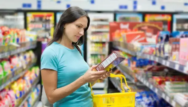 woman in grocery store reading the allergen label on a box